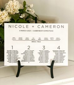 a table plan is displayed on a shelf with flowers in the backgroung