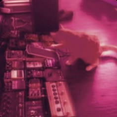 a cat sitting on top of a table next to remotes and other electronic equipment