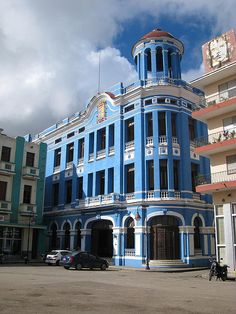 a large blue building sitting on the side of a road next to tall buildings with balconies