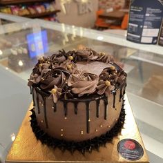 a chocolate cake sitting on top of a counter in front of a glass display case