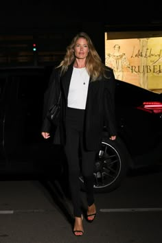 a woman in black and white is walking down the street with her hand on her hip