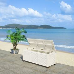 a white cooler sitting on top of a sandy beach next to the ocean with a palm tree