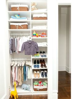 a white closet filled with lots of baby clothes and shoes next to a wooden floor