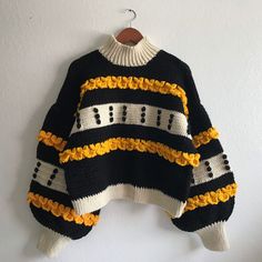 a black and yellow sweater hanging on a wall