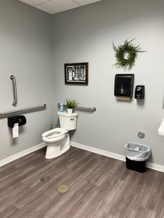 a bathroom with toilet, trash can and towel rack on the wall next to it