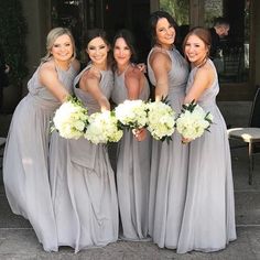 the bridesmaids are all wearing gray dresses and holding bouquets in their hands