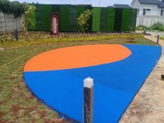 a blue and orange basketball court in the middle of a yard