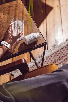 a person's hand resting on a table next to an empty glass and tube