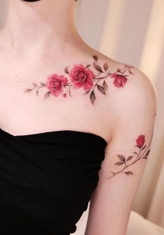 a woman wearing a black strapless dress with red roses on her chest and shoulder