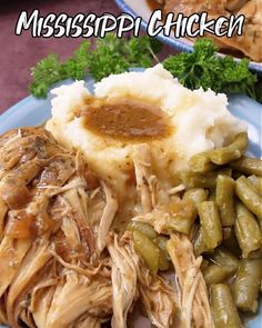 a blue plate topped with mashed potatoes and green beans covered in gravy