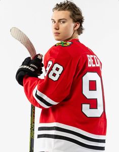 a young man holding a hockey stick and wearing a jersey