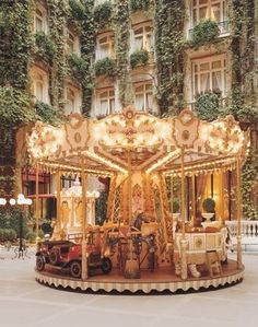 an elaborately decorated merry go round in front of a building with ivy growing on it