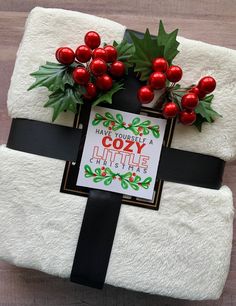 a white blanket with holly and red berries on it that says, have yourself a cozy little christmas