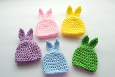 four crocheted hats with bunny ears on them, all in pastel colors