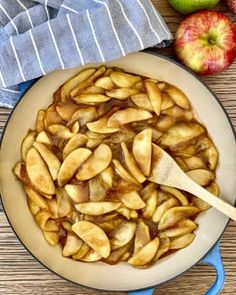 apples are being cooked in a skillet with a wooden spatula on the side