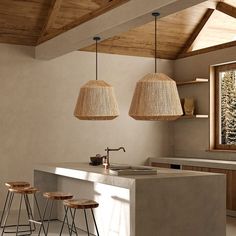 two lamps hanging from the ceiling above a kitchen island with stools in front of it