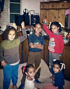 four children standing in a kitchen with their arms up