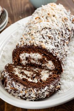 there is a chocolate roll on the plate with coconut sprinkles around it