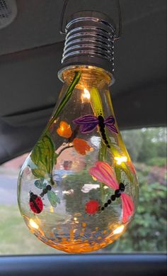 a light bulb hanging from the side of a car with flowers and bugs painted on it