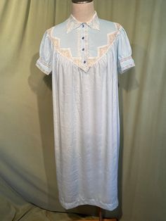 This lovely vintage nightgown is from the 1960s or early 70s. No labels or tags. No size tag. Bust measures 44", see measurements below.   Made of a rayon blend in light blue with lave collar & inserts on the bodice, yoked back & sleeves. Bodice & sleeves have pin pleats too. The gown slips over the head & has short sleeves. Buttons at the bodice with 4 plastic buttons. The gown reaches to mid calf.  Condition is very good.  No wear or stains. Charming! Measure yourself & know your measurements before buying! Please remember that vintage sizes run small. It is best to measure yourself, or a gown that fits you well. Measurements were taken with the garment lying flat. Measurements were taken without stretching.  Bust measured 2" below the underarms: 22" for a 44" or smaller bust Waist from Vintage Blue Sleepwear, Vintage Short Sleeve Sleepwear With Lace Trim, Vintage Dresses For Pajama Party, Vintage Lace Trim Sleepwear For Pajama Party, Vintage Nightgown For Sleepovers, Vintage Light Blue Summer Nightgown, Vintage Short Sleeve Nightgown For Sleep, Vintage Short Sleeve Nightgown, Vintage Light Blue Sleepwear With Lace Trim