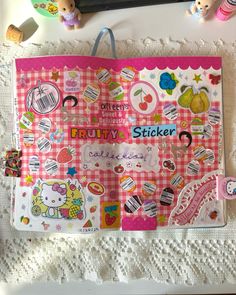 a pink and white hello kitty sticker book on a doily with other items around it