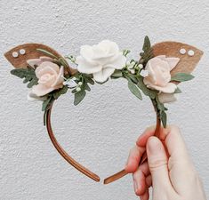 a hand holding a headband with flowers and leaves on it