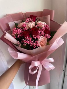 a bouquet of flowers is wrapped in pink paper