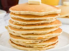 a stack of pancakes on a plate with butter and syrup in the backgroud