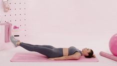 a woman laying on a pink exercise mat next to an exercise ball and gym equipment