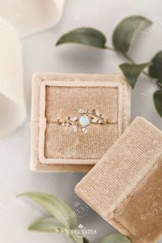 an engagement ring sits in a box next to some flowers