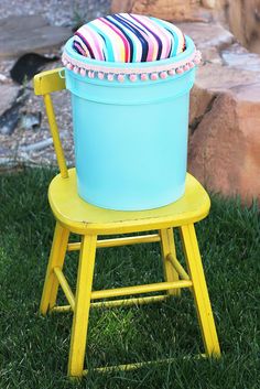 a yellow chair with a blue cooler on it's back sitting in the grass