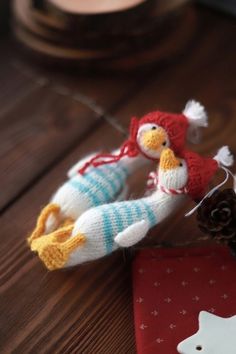 two knitted birds sitting on top of a wooden table next to a pine cone