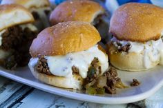 three hamburger sliders with cheese and onions on a plate