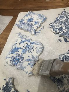 someone using a brush to paint blue and white flowers