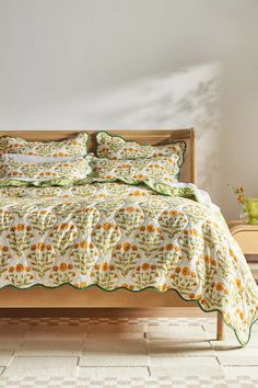 a bed with sunflowers and green trim on it in a white walled room