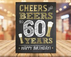 a sign that says cheers and beers to 60 years happy birthday on a wooden table