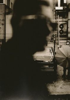 a person holding an umbrella standing next to a car in a garage with other cars