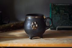 a black mug with a paw print on the inside sits on a wooden table next to other items