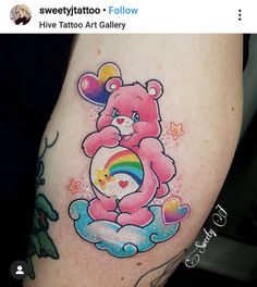 a pink teddy bear sitting on top of a rainbow