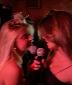 two beautiful women standing next to each other holding microphones