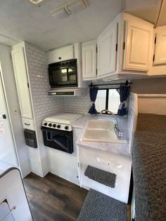 a kitchen area with sink, stove and microwave in a recreational vehicle or camper