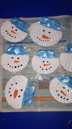 snowmen made out of paper plates sitting on top of a blue sheet of paper