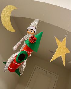 an elf is hanging from the ceiling next to some stars and a christmas tree ornament