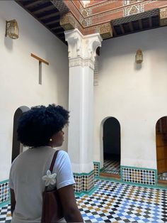 a woman standing in front of a white and black checkered floor with an archway