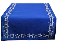 a blue table runner with white embroidery on the edges and an embroidered border at the top