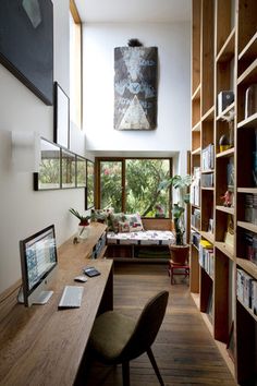 a home office with bookshelves, desk and computer on the table in front of large windows