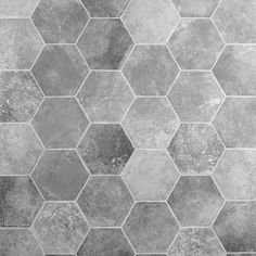 a gray and white tiled floor with hexagonal tiles on the bottom, in different shades