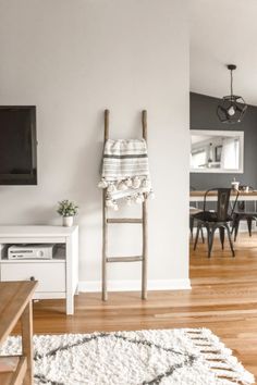 a living room filled with furniture and a flat screen tv mounted on the wall above a wooden ladder