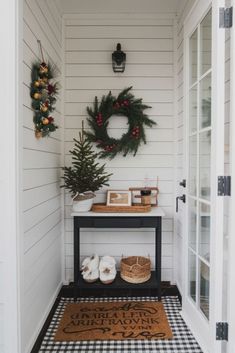 the entryway is decorated for christmas with wreaths and pine cones on the table