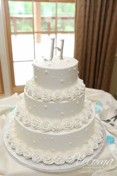 a three tiered white wedding cake with the number one on it's side